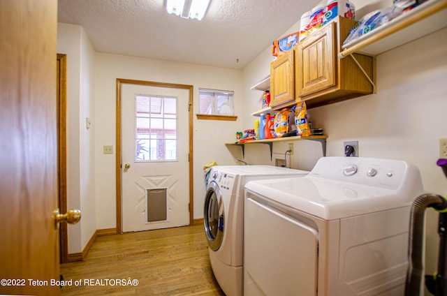 laundry area featuring washer and dryer, a textured ceiling, light hardwood / wood-style flooring, hookup for an electric dryer, and hookup for a washing machine