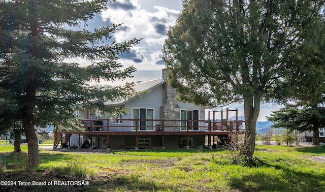 back of property featuring a deck and a yard