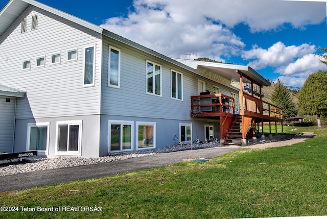 back of house with a deck and a lawn