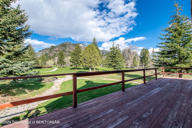 wooden deck featuring a mountain view and a lawn