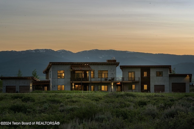 back house at dusk with a mountain view and a balcony