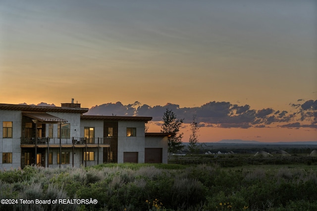 back house at dusk featuring a balcony