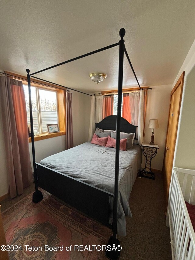 bedroom featuring dark colored carpet and a textured ceiling