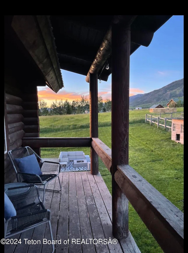 deck at dusk featuring a mountain view, outdoor lounge area, and a yard