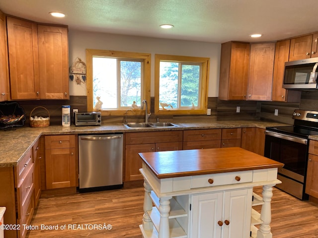 kitchen featuring backsplash, stainless steel appliances, sink, and light wood-type flooring