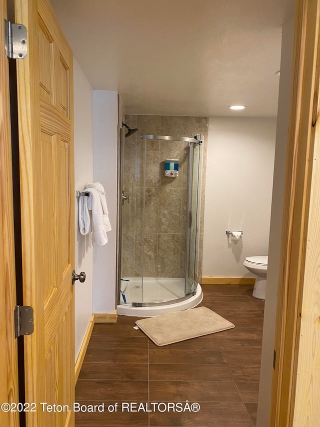 bathroom with toilet and a shower with shower door