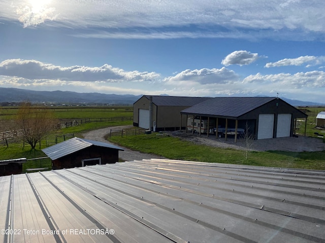 exterior space featuring a front lawn, a garage, an outdoor structure, a rural view, and a mountain view