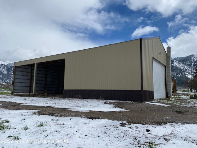 snow covered structure featuring a mountain view and a garage