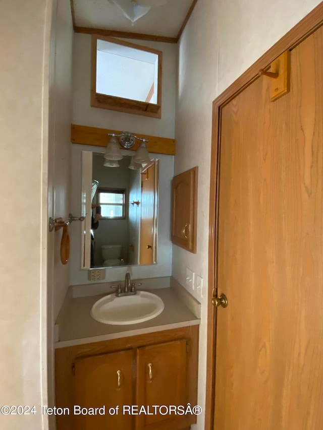 bathroom featuring vanity, toilet, and crown molding