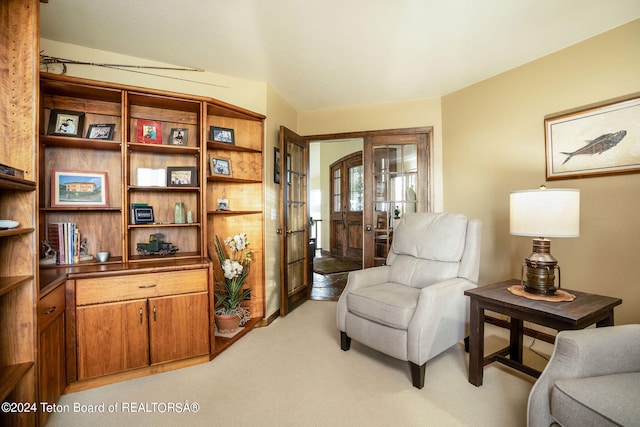 living area featuring lofted ceiling, light carpet, and french doors