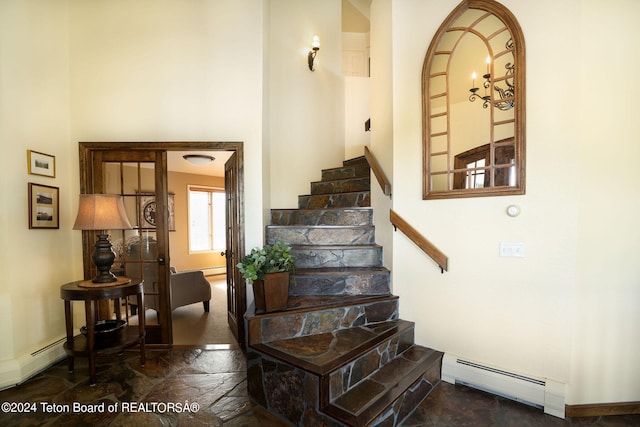 stairway with a baseboard radiator and dark tile floors