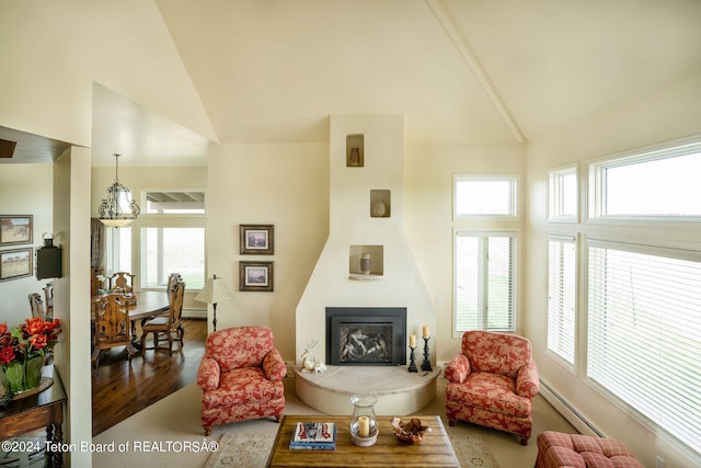 living room with plenty of natural light, high vaulted ceiling, wood-type flooring, and a baseboard heating unit