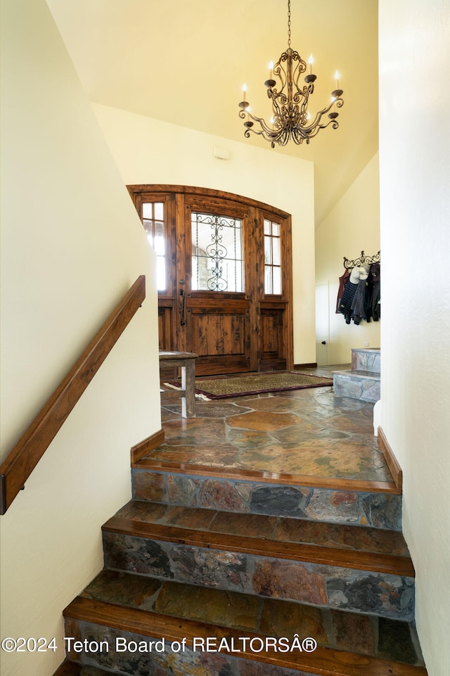 stairway with an inviting chandelier and vaulted ceiling