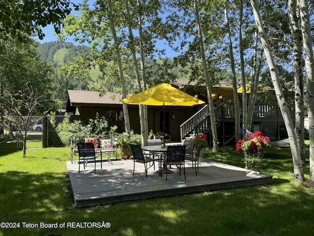 exterior space with fence, a yard, a wooden deck, a gate, and outdoor dining space