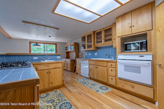 kitchen with light hardwood / wood-style floors, white appliances, decorative light fixtures, rail lighting, and tasteful backsplash