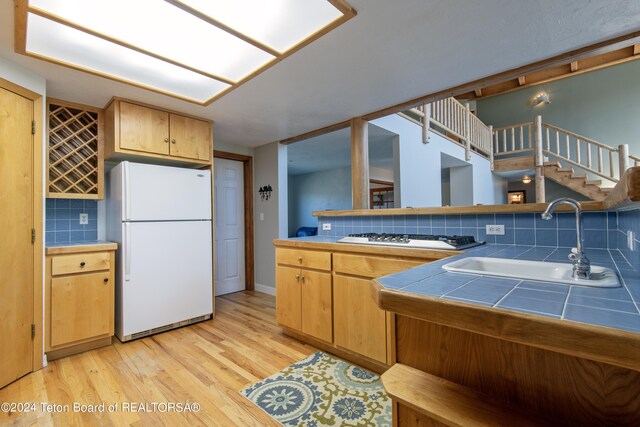 kitchen with sink, white refrigerator, tasteful backsplash, and tile counters