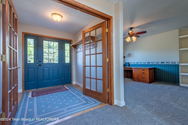 foyer entrance featuring french doors, carpet, and ceiling fan