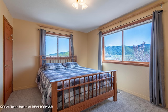 bedroom with carpet, multiple windows, and a mountain view