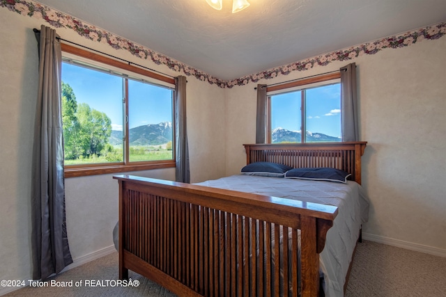 carpeted bedroom featuring multiple windows and a mountain view