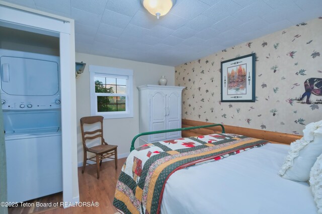 4193 Old Irwin Rd, Irwin, ID 83428 - bedroom featuring stacked washer / drying machine, light wood finished floors, and wallpapered walls