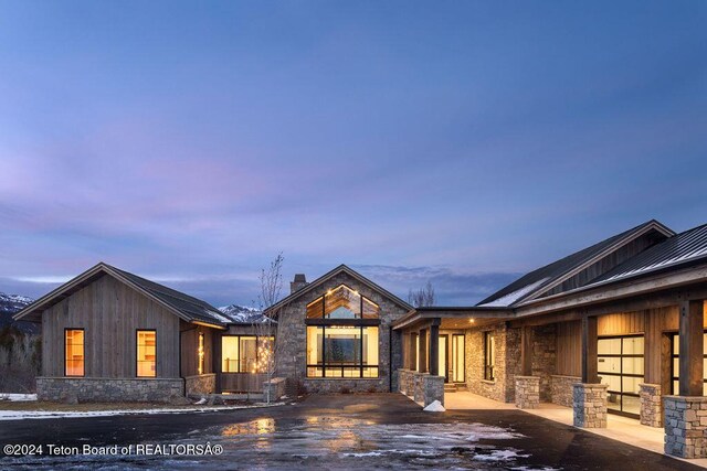 view of front of house featuring stone siding, a chimney, metal roof, and a standing seam roof