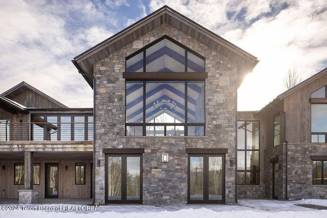 rear view of property with stone siding and french doors