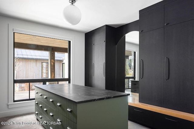 kitchen featuring dark countertops, a center island, dark cabinetry, and arched walkways