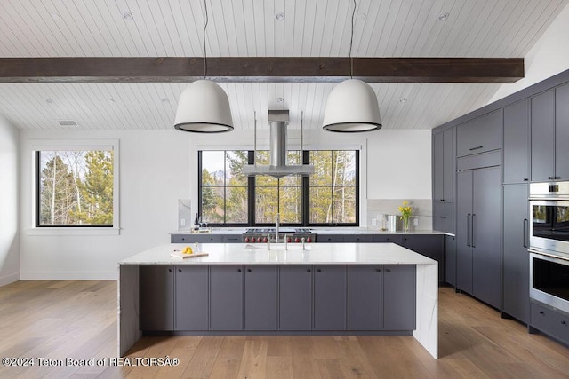 kitchen featuring island range hood, gray cabinetry, light wood-style floors, light countertops, and beam ceiling