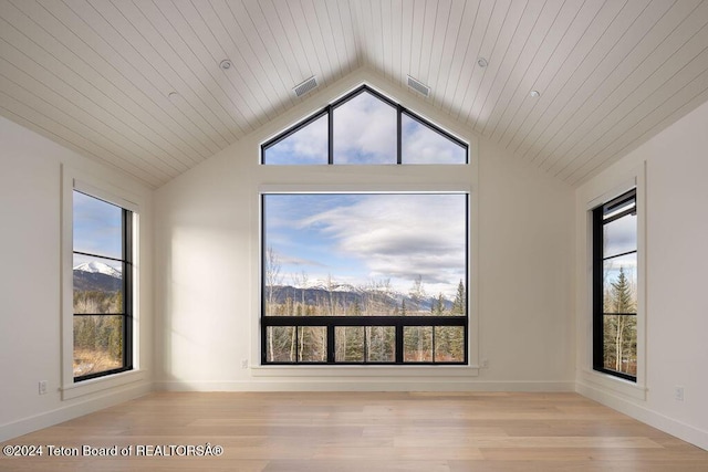 empty room featuring vaulted ceiling, wood finished floors, visible vents, and baseboards