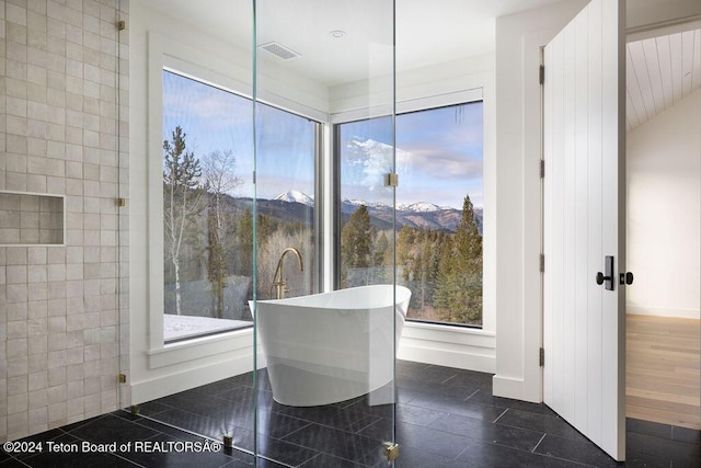 bathroom featuring a freestanding tub, visible vents, a mountain view, and baseboards