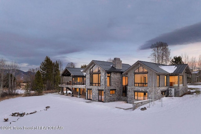 snow covered house with metal roof, a standing seam roof, and a chimney