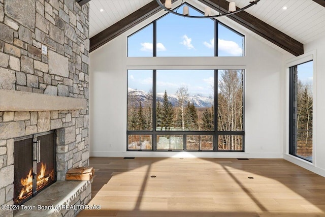 living area featuring high vaulted ceiling, a fireplace, beam ceiling, and wood finished floors