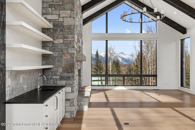 interior space with an inviting chandelier, a sink, wood finished floors, high vaulted ceiling, and beamed ceiling