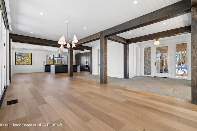 unfurnished living room featuring a chandelier, light wood-style flooring, recessed lighting, visible vents, and beamed ceiling