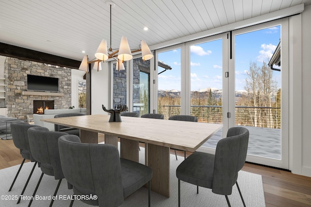 dining room featuring plenty of natural light, wood finished floors, and a stone fireplace