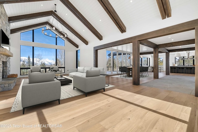 living area with a fireplace, high vaulted ceiling, wood finished floors, and beamed ceiling