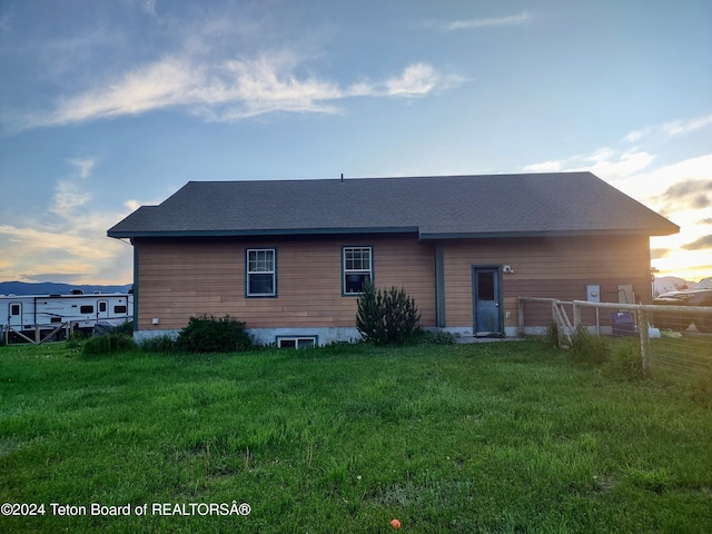 back house at dusk with a lawn