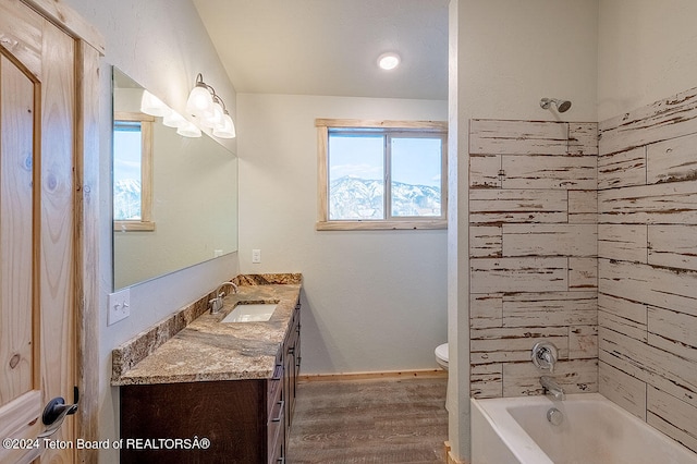 full bathroom featuring hardwood / wood-style flooring, vanity, tiled shower / bath, and toilet