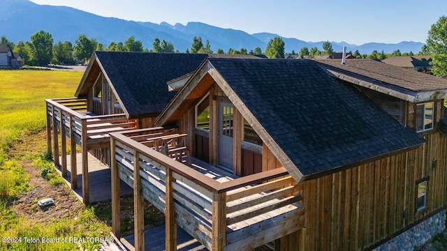 back of property with a deck with mountain view and a yard