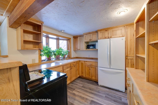 kitchen featuring white fridge, black microwave, wood-type flooring, sink, and a textured ceiling