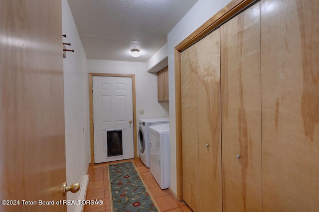 laundry area with washer and clothes dryer, light tile flooring, and cabinets