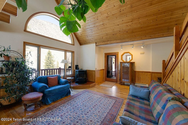 living room featuring a wood stove, hardwood / wood-style flooring, rail lighting, wood ceiling, and high vaulted ceiling