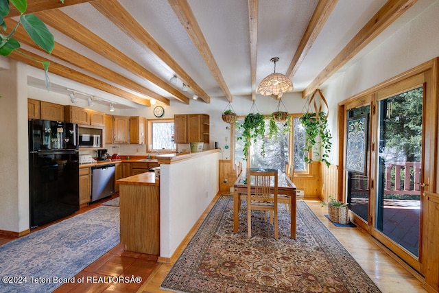 kitchen featuring beam ceiling, track lighting, hanging light fixtures, sink, and appliances with stainless steel finishes