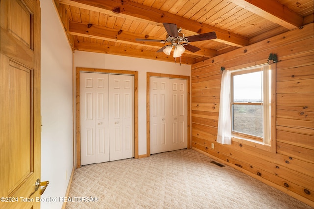 unfurnished bedroom with beam ceiling, wooden walls, light colored carpet, and wooden ceiling