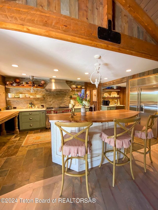 kitchen with green cabinets, tasteful backsplash, wall chimney exhaust hood, dark hardwood / wood-style flooring, and stainless steel built in refrigerator