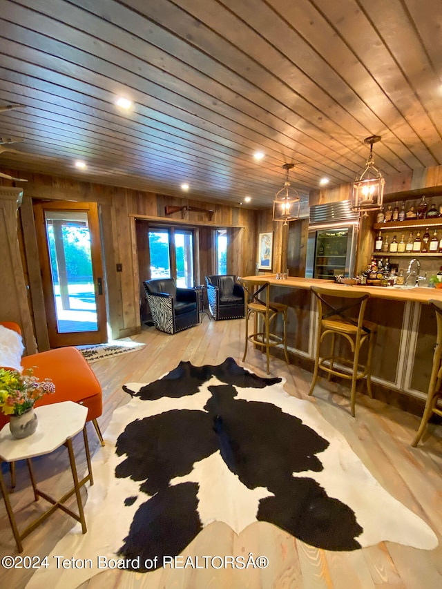 living room featuring wooden walls, light hardwood / wood-style flooring, and wooden ceiling