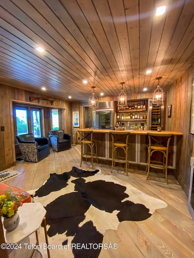 living room with wooden ceiling, bar area, wood walls, and light hardwood / wood-style floors