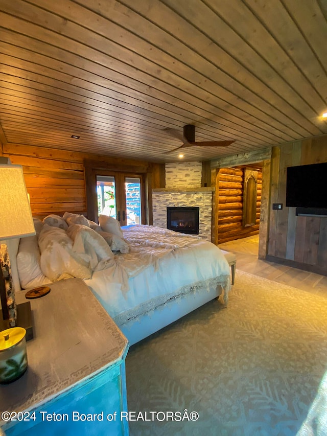 bedroom with wooden ceiling, a fireplace, log walls, and light wood-type flooring