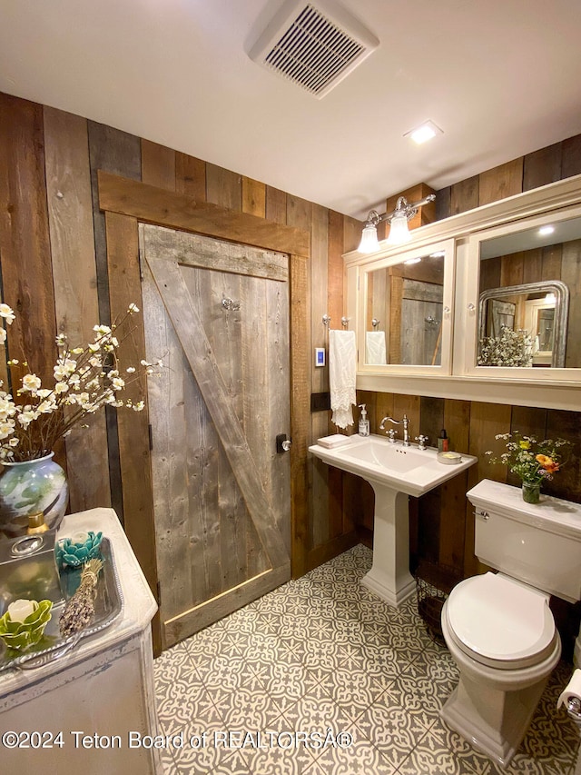 bathroom featuring wood walls, tile floors, and toilet