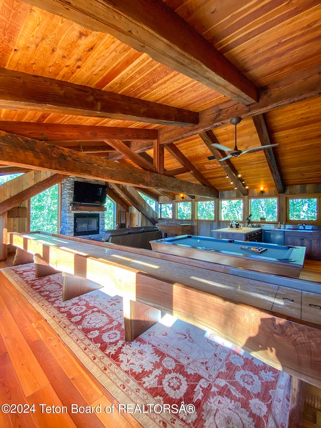 interior space with a large fireplace, light hardwood / wood-style flooring, vaulted ceiling with beams, wood ceiling, and ceiling fan